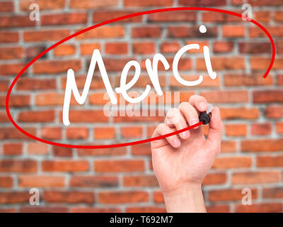 Man mano che scrive Merci (grazie in francese) con pennarello nero su schermo visivo. Foto Stock