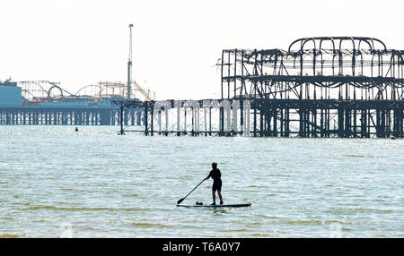 Brighton Regno Unito 30 aprile 2019 - Una racchetta boarder gode il caldo clima soleggiato off Hove spiaggia vicino al Molo Ovest questa mattina con la previsione di raggiungere in alta teens in alcune parti del sud est di oggi. Credito: Simon Dack/Alamy Live News Foto Stock