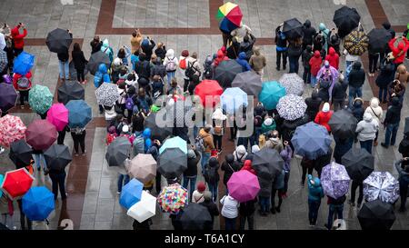 Monaco di Baviera, Germania. 30 apr, 2019. I turisti stand con ombrelloni sulla Marienplatz quando piove. Credito: Sina Schuldt/dpa/Alamy Live News Foto Stock