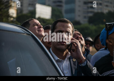 Auto proclamato presidente ad interim del Venezuela, Juan Guaidó, è visto parlare al telefono durante un colpo di stato militare di Caracas. Militare venezuelano che sostengono il venezuelano leader dell opposizione Juan Guaido ha preso per la strada con le loro armi insieme con anti governo manifestanti in un colpo di stato militare contro il governo socialista guidato da presidente Nicolas Maduro. Foto Stock