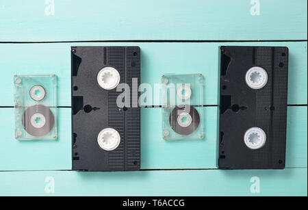 Cassette video e audio cassette su un turchese tavolo in legno. Video retrò e tecnologia audio. Vista dall'alto. Foto Stock