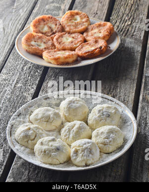 Tradizionalmente, Russo materie e frittelle fritte con ricotta. La cheesecake su un di legno tavolo rustico. Il processo di cottura. Foto Stock