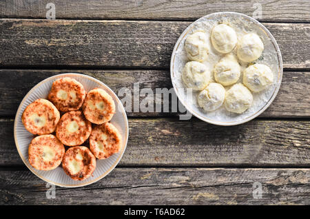 La cheesecake su un di legno tavolo rustico. Tradizionalmente, Russo materie e frittelle fritte con ricotta. Il processo di cottura. Vista dall'alto. Foto Stock