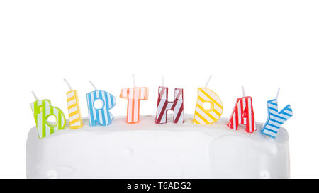 A strisce colorate candele formante la parola compleanno sul bianco torta smerigliato isolati su sfondo bianco. Foto Stock