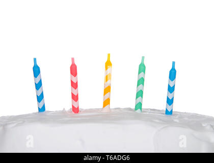 A strisce colorate compleanno candele sul bianco torta smerigliato isolati su sfondo bianco Foto Stock