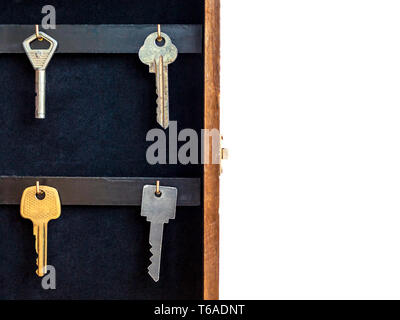 Chiavi appeso sul Golden ganci in una parete titolare di chiave su sfondo bianco. Ipoteca, assicurazione, il concetto di sicurezza. Foto Stock