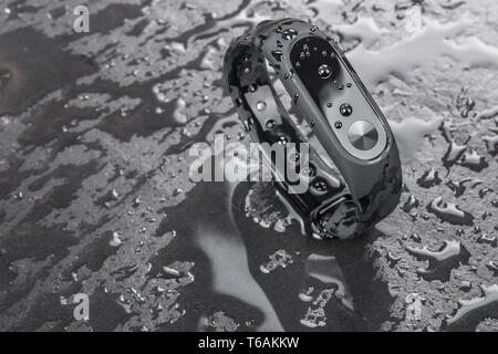 Wet braccialetto di fitness, fitness tracker su un nero ardesia sfondo con gocce di acqua Foto Stock