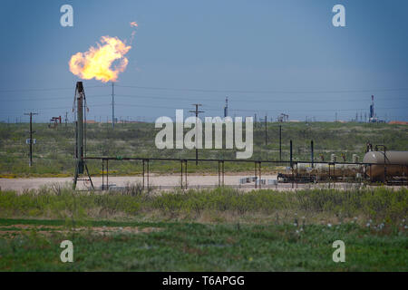 Midland, County / Stati Uniti d'America - 21 Aprile 2019: l'eccesso di gas naturale viene bruciata in un pozzo di petrolio sito. Foto Stock