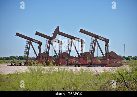 Midland County, Texas, Stati Uniti d'America - 21 Aprile 2019 : un array di unità di pompaggio in una direzione ben nel bacino Permiano oilfield. Foto Stock