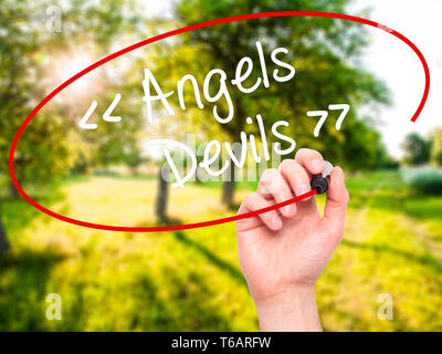 Man mano che scrive angeli - i diavoli con pennarello nero su schermo visivo. Foto Stock