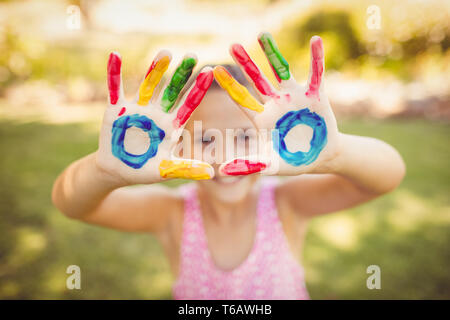 Bambina facendo un triangolo con il suo dipinto le mani per la fotocamera Foto Stock