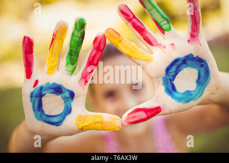 Bambina facendo un triangolo con il suo dipinto le mani per la fotocamera Foto Stock