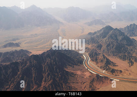 Vista aerea di una autostrada curvatura stradale tra brulla montagne rocciose e il deserto a sud della penisola del Sinai vicino a Sharm El Sheikh Foto Stock