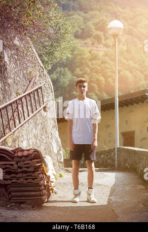 Ragazzo adolescente in sportswear in piedi in un villaggio di montagna Foto Stock