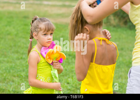 La bambina guarda come mia madre trecce di sua sorella Foto Stock