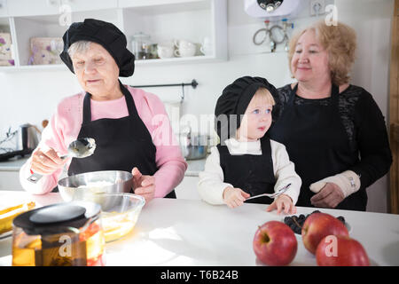 La famiglia felice rendendo pancake in cucina. Mele sul tavolo Foto Stock