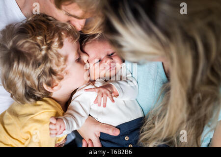 I giovani genitori con un neonato e piccolo bimbo figlio a casa, un close-up. Foto Stock