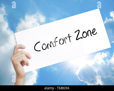 Comfort Zone segno su carta bianca. Man mano che tiene la carta con testo. Isolato su sfondo cielo Foto Stock