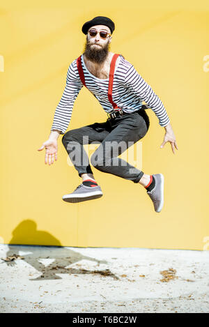 Ritratto di un elegante uomo gioioso salta su sfondo colorato all'aperto Foto Stock