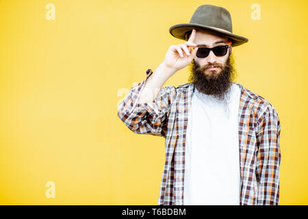 Ritratto di un fresco elegante Uomo in camicia e hat in posa sul luminoso sfondo giallo Foto Stock