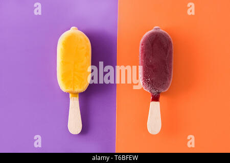 La fragola e orange popsicles su viola e sfondo arancione. Foto Stock