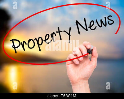 Man mano che scrive Property News con pennarello nero su schermo visivo. Foto Stock