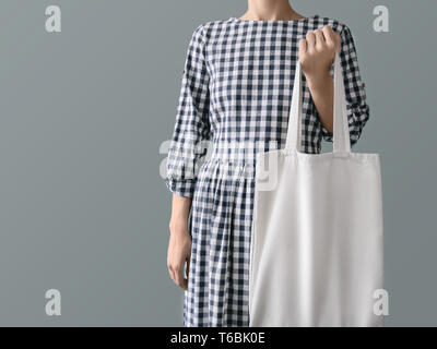 Tela vuota tote bag eco-friendly prodotto una donna in un plaid abito di cotone è in possesso di un bianco riutilizzabile shopping bag Foto Stock