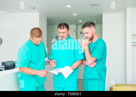 Gruppo di personale medico per discutere dei risultati del paziente in clinica. I professionisti del settore sanitario avente la discussione in ospedale. Medico esperto spiegando SMT Foto Stock