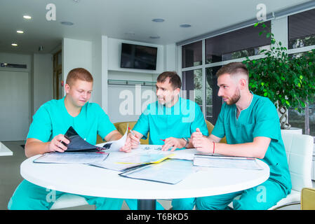 Gruppo di personale medico per discutere dei risultati del paziente in clinica. I professionisti del settore sanitario avente la discussione in ospedale. Medico esperto spiegando SMT Foto Stock