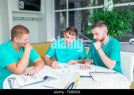 Gruppo di personale medico per discutere dei risultati del paziente in clinica. I professionisti del settore sanitario avente la discussione in ospedale. Medico esperto spiegando SMT Foto Stock