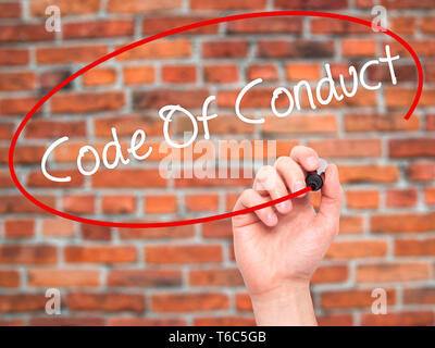 Man mano la scrittura di codice di condotta con pennarello nero su schermo visivo Foto Stock
