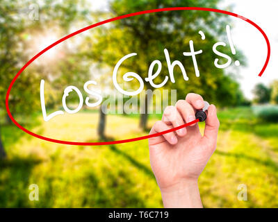 Man mano che scrive Los geht's! (Qui andiamo in tedesco) con pennarello nero su schermo visivo Foto Stock