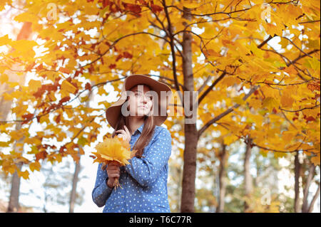 Bella giovane donna tenendo un mazzo di foglie di autunno Foto Stock