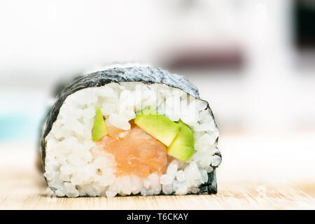 Il Sushi con salmone, avocado, riso nelle alghe marine e bastoncini sul tavolo di legno Foto Stock