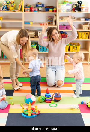 Un gruppo di bambini i bambini giocando con colorati giocattoli educativi insieme con le madri in vivaio per bambini Sala giochi Foto Stock