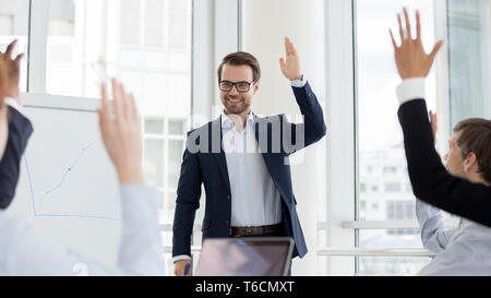 Happy business coach e team alzare le mani impegnate in votazione Foto Stock