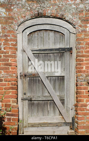 Vecchia porta di legno in un muro di mattoni Foto Stock