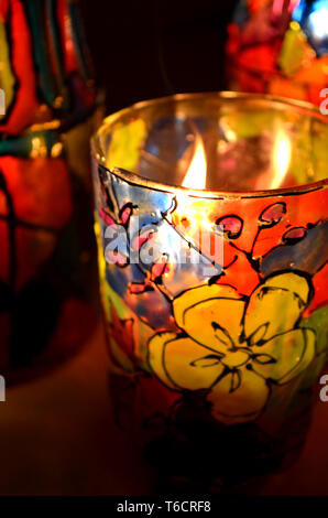 Bicchiere Porta candele verniciato vetro macchiato di vernici con una candela che brucia all'interno Foto Stock