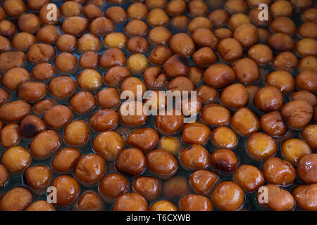 Cumulo di Gulab Jamun dolci immerso in cardamomo aromatizzate lo sciroppo zuccherino Foto Stock