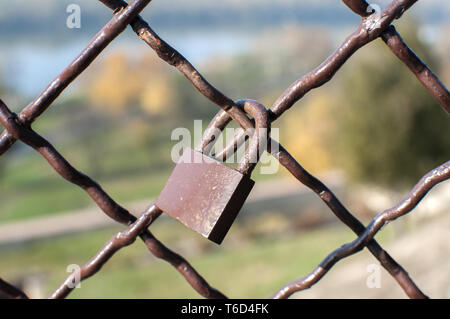 Lucchetto in metallo bloccato su weathered vintage maglia metallica closeup Foto Stock