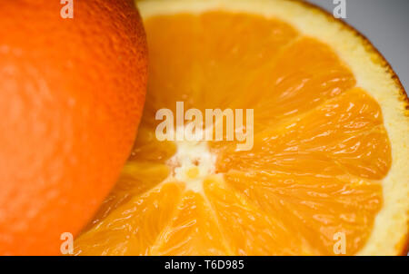 Macro Closeup di fresco succosa arancione divisa in due metà di un lato invertito con buona consistenza della polpa e buccia Foto Stock