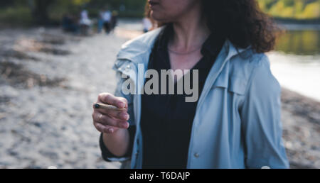 La persona fumare marijuana giunto all'esterno. Giunto di cannabis in mano Foto Stock