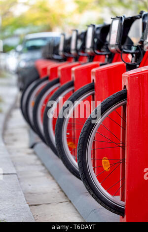 Molti noleggio in una riga. Red biciclette stand su un parcheggio in affitto. Eco-friendly concetto di trasporto. Foto Stock