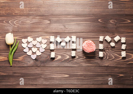 Una frase che amo mamma fatta con tulipano bianco e tratta su sfondo di legno, vista dall'alto. La festa della mamma composizione Foto Stock