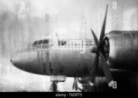 Aeroplano dietro la finestra con le gocce di pioggia Foto Stock