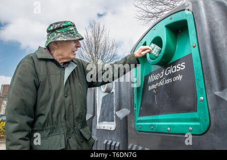 Gettando in un misto di bottiglie di vetro e vasi per re-cycling presso un punto di raccolta vicino al supermercato locale. Foto Stock
