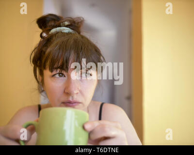 Assonnato giovane donna attraente con una tazza di caffè al mattino a casa Foto Stock