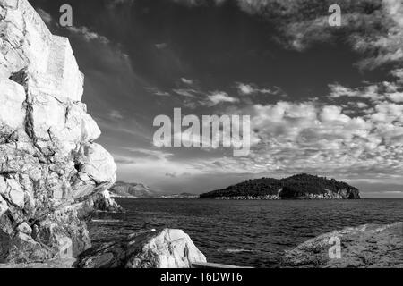 Guardando a sud verso l'isola di Lokrum, dal di sotto del Buža 2 bar al di fuori dalle mura della città: Dubrovnik, Croazia. Versione in bianco e nero Foto Stock