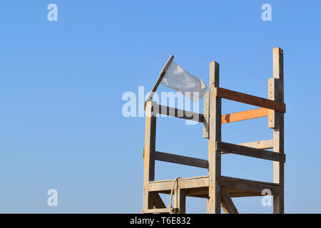 Bandiera bianca nel vento su una sedia di guardia del mare Foto Stock