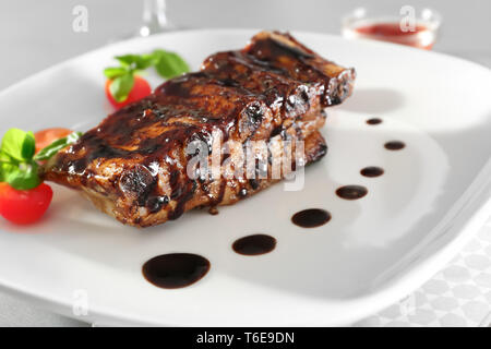 Deliziosi Costolette alla griglia con salsa di pomodori e sulla piastra, primo piano Foto Stock